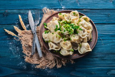 Lezzetli ev yapımı etli hamur köfteleri ya da ahşap masaya taze maydanoz serpiştirilmiş Rus pelmeni, kopya alanı, yukarıdan görüş.