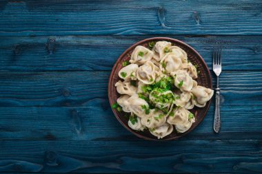 Lezzetli ev yapımı etli hamur köfteleri ya da ahşap masaya taze maydanoz serpiştirilmiş Rus pelmeni, kopya alanı, yukarıdan görüş.