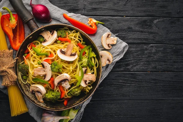 Macarrão com verduras em uma panela de ato de fritar. Cozinha Asiática Pasta. Vista superior. Espaço livre. Em um fundo de madeira .; — Fotografia de Stock