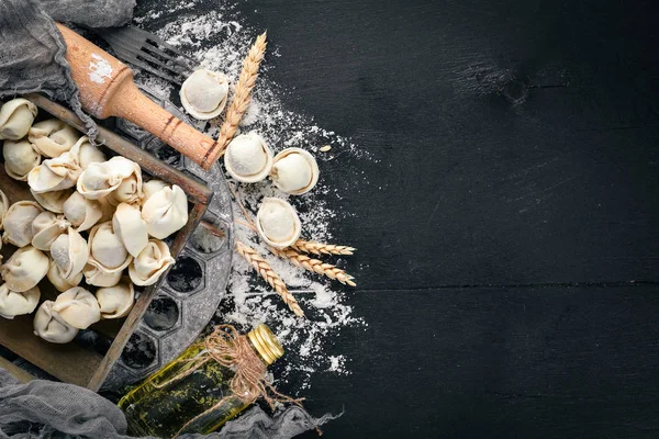 Traditional russian pelmeni, ravioli, dumplings with meat on black concrete background. Top view. Copyspace. — Stock Photo, Image