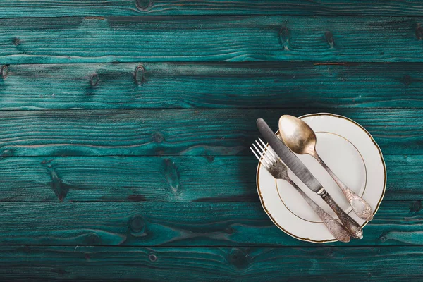 Plate and old cutlery. On a wooden background. Top view. Free space for text.