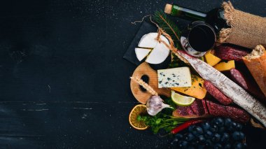 Bir şişe şarap, peynir ve ahşap arka plan üzerinde geleneksel sosis. Brie peyniri, mavi peynir, gorgonzola, fuete, salam. Metin için özgür yer. Üstten Görünüm.