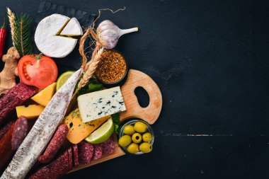 Peynir ve ahşap arka plan üzerinde geleneksel sosis ürün yelpazesine. Brie peyniri, mavi peynir, gorgonzola, fuete, salam. Metin için özgür yer. Üstten Görünüm.