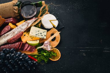Bir şişe şarap, peynir ve ahşap arka plan üzerinde geleneksel sosis. Brie peyniri, mavi peynir, gorgonzola, fuete, salam. Metin için özgür yer. Üstten Görünüm.