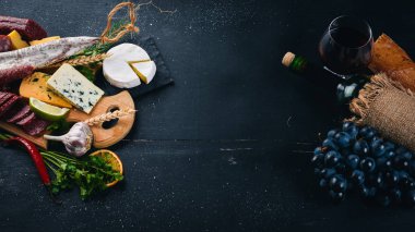 Bir şişe şarap, peynir ve ahşap arka plan üzerinde geleneksel sosis. Brie peyniri, mavi peynir, gorgonzola, fuete, salam. Metin için özgür yer. Üstten Görünüm.