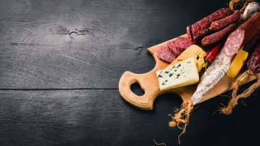 Peynir ve ahşap arka plan üzerinde geleneksel sosis ürün yelpazesine. Brie peyniri, mavi peynir, gorgonzola, fuete, salam. Metin için özgür yer. Üstten Görünüm.