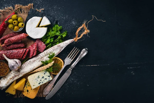 Assortiment van kaas en traditionele worstjes op een houten achtergrond. Brie-kaas, blauwe kaas, gorgonzola, fuete, salami. Vrije ruimte voor tekst. Bovenaanzicht. — Stockfoto