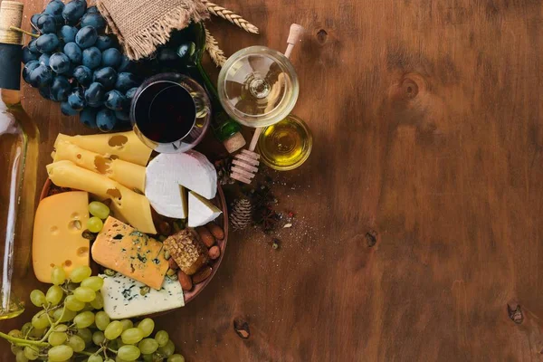 와인과 치즈, 꿀, 견과 및 향미료 나무 테이블에의 큰 구색의 병. 최고의 볼 수 있습니다. 텍스트에 대 한 여유 공간. — 스톡 사진
