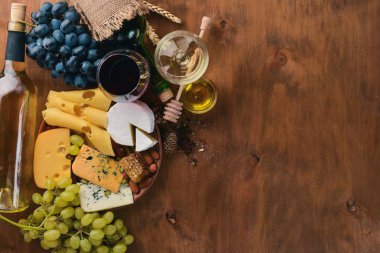 Bir şişe şarap ve peynir, bal, fındık ve Baharatlar, ahşap bir masa üzerinde büyük bir ürün yelpazesine. Üstten Görünüm. Metin için boş alan.
