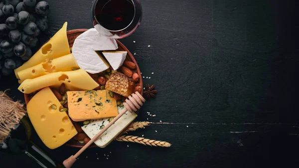 Sortimento de queijos, uma garrafa de vinho, mel, nozes e especiarias, em uma mesa de madeira. Vista superior. Espaço livre para texto . — Fotografia de Stock