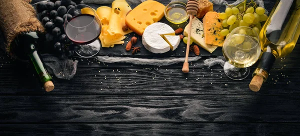 Ett stort sortiment av ostar, brieost, gorgonzola, ädelost, druvor, honung, nötter, rött och vitt vin, på ett träbord. Ovanifrån. Ledigt utrymme för text. — Stockfoto