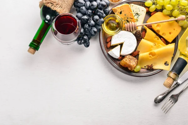 De achtergrond van het voedsel met kaas. Blokken van beschimmelde kaas, honing, druiven en noten over op witte achtergrond. Kopieer ruimte. Bovenaanzicht. — Stockfoto