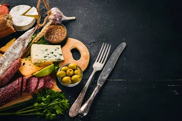 Surtido de quesos y embutidos tradicionales sobre fondo de madera. Queso brie, queso azul, gorgonzola, fuete, salami. Espacio libre para texto. Vista superior . — Foto de Stock