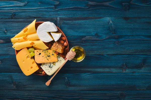 Uvas, vinho tinto, queijos, mel e nozes sobre um fundo de madeira. Vista superior . — Fotografia de Stock