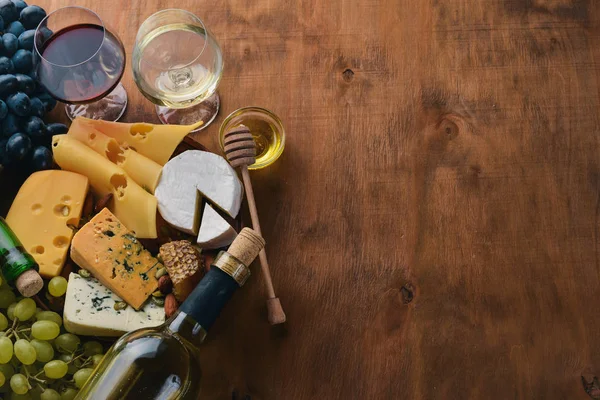 ワインとチーズ、蜂蜜、ナッツ、スパイス、木製のテーブルの大規模な品揃えのボトル。平面図です。テキスト用の空き容量. — ストック写真