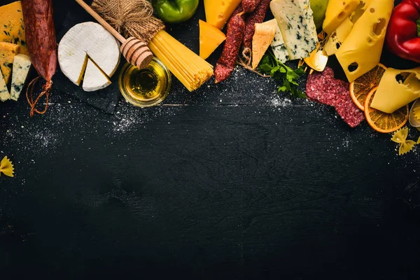 Çeşitli peynir, sosis, şaraplar, geleneksel baharat ve ahşap arka plan üzerinde taze sebze. Peynir brie, mavi peynir, gorgonzola, fuete, salam. İtalyan ve İspanyol mutfağının. Metin için özgür yer. Üstten Görünüm.