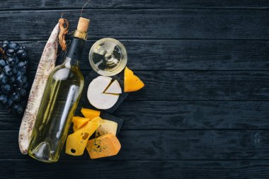 Bir şişe şarap, peynir ve ahşap arka plan üzerinde geleneksel sosis. Brie peyniri, mavi peynir, gorgonzola, fuete, salam. Metin için özgür yer. Üstten Görünüm.
