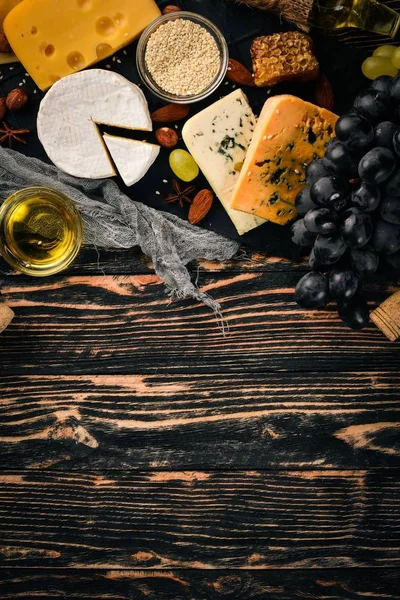 Grapes, red wine, cheeses, honey and nuts on a wooden background. Top view.