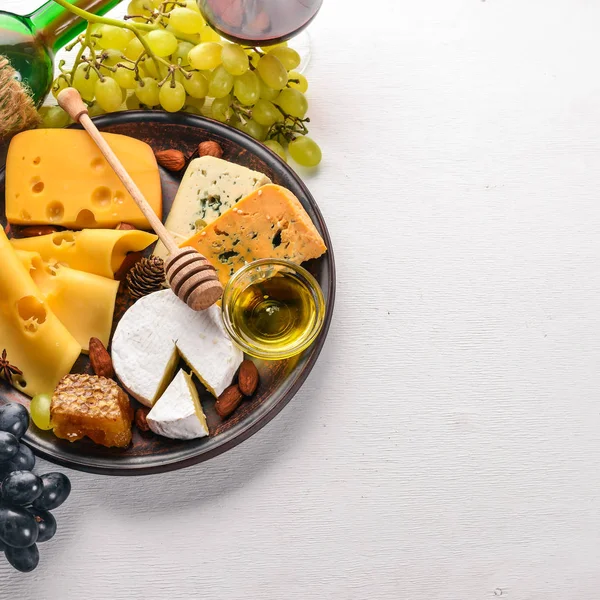 Food background with cheese. Blocks of moldy cheese, grapes, honey, nuts over on white background. Copy space. Top view.