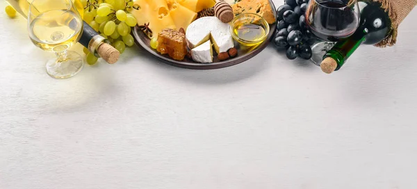 Food background with cheese. Blocks of moldy cheese, grapes, honey, nuts over on white background. Copy space. Top view.