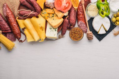 Çeşitli peynirler ve geleneksel sosis ve sebze Beyaz ahşap zemin üzerinde. Peynir brie, mavi peynir, gorgonzola, fuete, salam. Geleneksel İtalyan mutfağı. Metin için özgür yer. Üstten Görünüm.