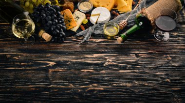 Ürün yelpazesine peynirler, brie peyniri, gorgonzola, mavi peynir, üzüm, bal, fındık, kırmızı ve beyaz şarap, ahşap bir masa üzerinde bir büyük. Üstten Görünüm. Metin için boş alan.