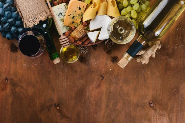ワインとチーズ ナッツ スパイス 木製のテーブルの大規模な品揃えのボトル 平面図です テキスト用の空き容量 — ストック写真