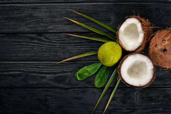 Coconut and lime. Fresh fruits. On a wooden background. Top view. Free space for text.