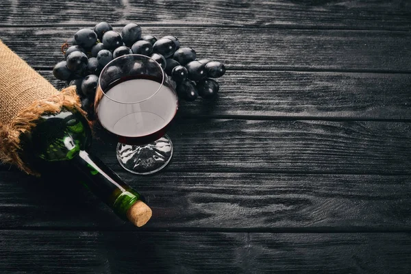 Uma Garrafa Vinho Com Copos Uvas Fundo Madeira Preta Espaço — Fotografia de Stock