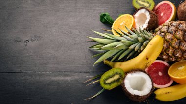 Taze tropikal meyve. Ananas, Hindistan cevizi, kivi, portakal, nar, greyfurt. Ahşap bir arka plan üzerinde. Üstten Görünüm. Metin için boş alan.