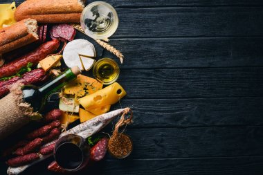 Bir şişe şarap, peynir ve ahşap arka plan üzerinde geleneksel sosis. Brie peyniri, mavi peynir, gorgonzola, fuete, salam. Metin için özgür yer. Üstten Görünüm.