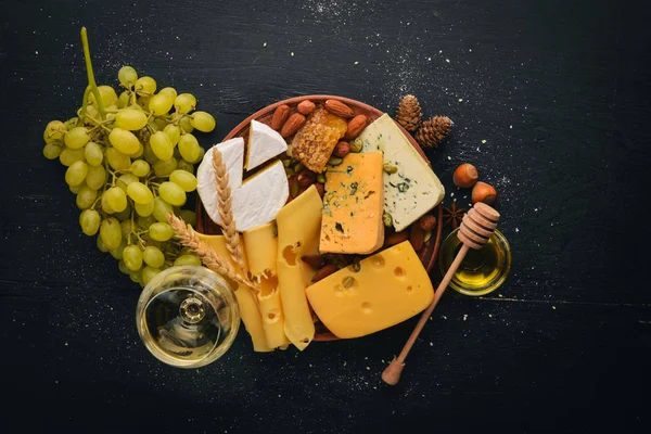 Assortment of cheeses, a bottle of wine, honey, nuts and spices, on a wooden table. Top view. Free space for text.