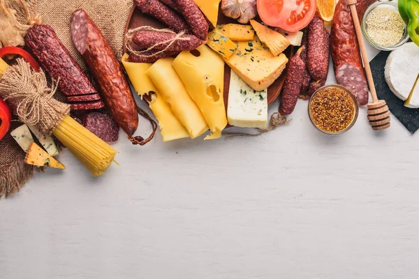 Peynir ve ahşap arka plan üzerinde geleneksel sosis ürün yelpazesine. Brie peyniri, mavi peynir, gorgonzola, fuete, salam. Metin için özgür yer. Üstten Görünüm.
