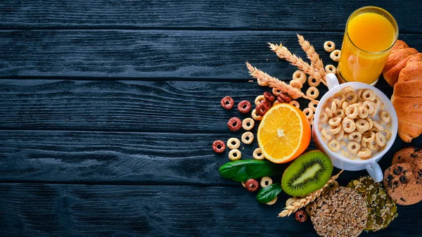 Fitness breakfast, muesli, milk, fruits, nuts and seeds, on a wooden surface. Top view. Free space for text.