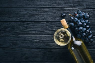 Bir şişe şarap gözlük ve üzüm siyah ahşap zemin ile. Metin için özgür yer. Üstten Görünüm.