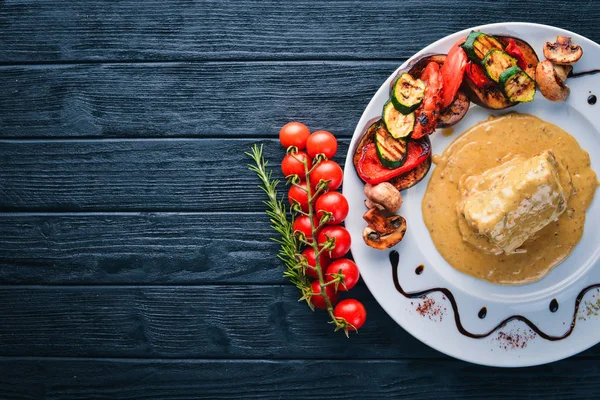 Eti biftek sosu ve ızgara sebzeler. Biftek Voronov. Ahşap bir arka plan üzerinde. Metniniz için boş alan. Üstten Görünüm.