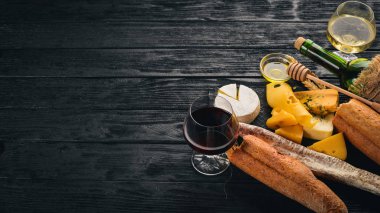 Bir şişe şarap, peynir ve ahşap arka plan üzerinde geleneksel sosis. Brie peyniri, mavi peynir, gorgonzola, fuete, salam. Metin için özgür yer. Üstten Görünüm.