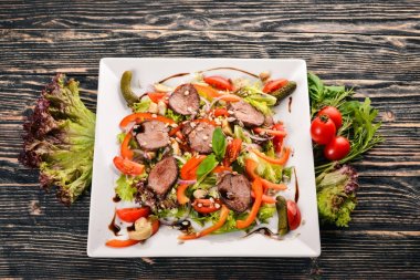 Dana salata, marul ve plaka üzerinde taze sebze. Ahşap bir arka plan üzerinde. Üstten Görünüm. Metin için boş alan.