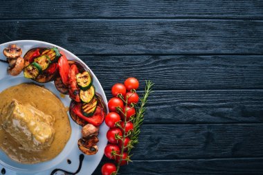 Eti biftek sosu ve ızgara sebzeler. Biftek Voronov. Ahşap bir arka plan üzerinde. Metniniz için boş alan. Üstten Görünüm.