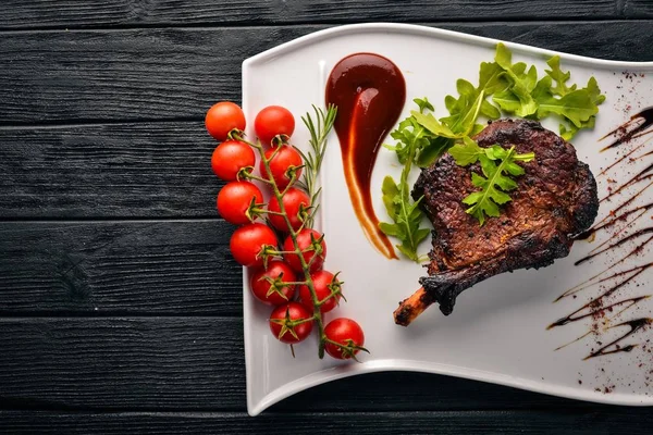 Steak on a bone with tomatoes and a hazelnut. Steak Fiorentino. On a wooden background. Free space for your text. Top view.