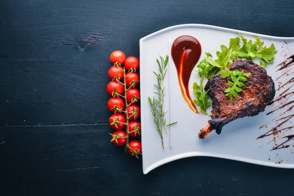 Steak on a bone with tomatoes and a hazelnut. Steak Fiorentino. On a wooden background. Free space for your text. Top view.