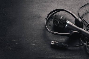 Kulaklık ve mikrofon ahşap bir siyah masa üzerinde. Stüdyo. Üstten Görünüm. Metin için özgür yer. Kopya alanı.