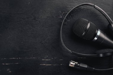 Kulaklık ve mikrofon ahşap bir siyah masa üzerinde. Stüdyo. Üstten Görünüm. Metin için özgür yer. Kopya alanı.