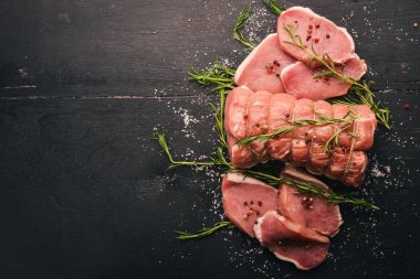 Biberiye ve baharat siyah ahşap zemin ile çiğ et sığır filetosu. Üstten Görünüm. Metin için boş alan