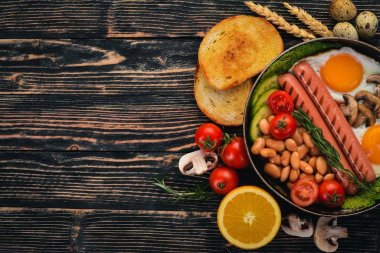 İngiliz kahvaltısı - kızarmış yumurta, fasulye, domates, mantar, pastırma ve tost. Üstten Görünüm. Ahşap bir arka plan üzerinde.