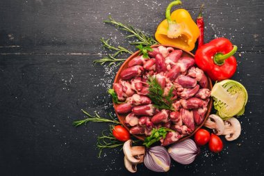 Çiğ tavuk kupa rosemary ile yemek pişirmek için hazır plaka üzerinde ve üzerinde baharat siyah ahşap arka plan. Üstten Görünüm. Metin için boş alan.