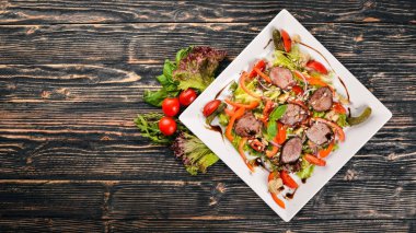 Dana salata, marul ve plaka üzerinde taze sebze. Ahşap bir arka plan üzerinde. Üstten Görünüm. Metin için boş alan.