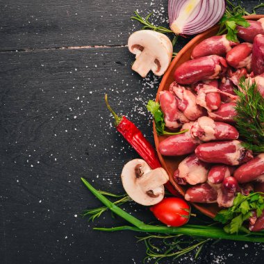 Çiğ tavuk kupa rosemary ile yemek pişirmek için hazır plaka üzerinde ve üzerinde baharat siyah ahşap arka plan. Üstten Görünüm. Metin için boş alan.