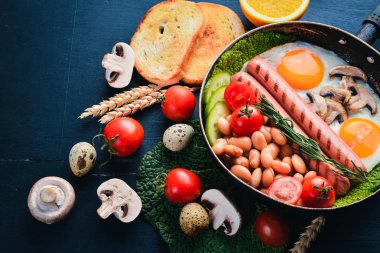 İngiliz kahvaltısı. Kızarmış yumurta, sosis, pastırma, fasulye, tost, domates, kahve fincanı taştan masada. Metin alanı olan Üstten Görünüm