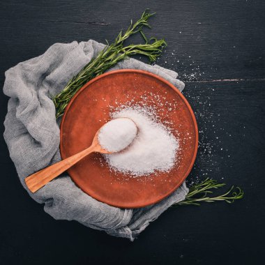 Bir plaka üzerinde bir tahta kaşık tuz. Ahşap bir arka plan üzerinde. Üstten Görünüm. Metin için boş alan.